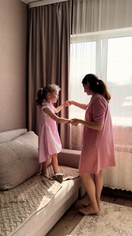 Mom and her small daughter having dance party in living room at home. energetic mother daughter play creating precious memories