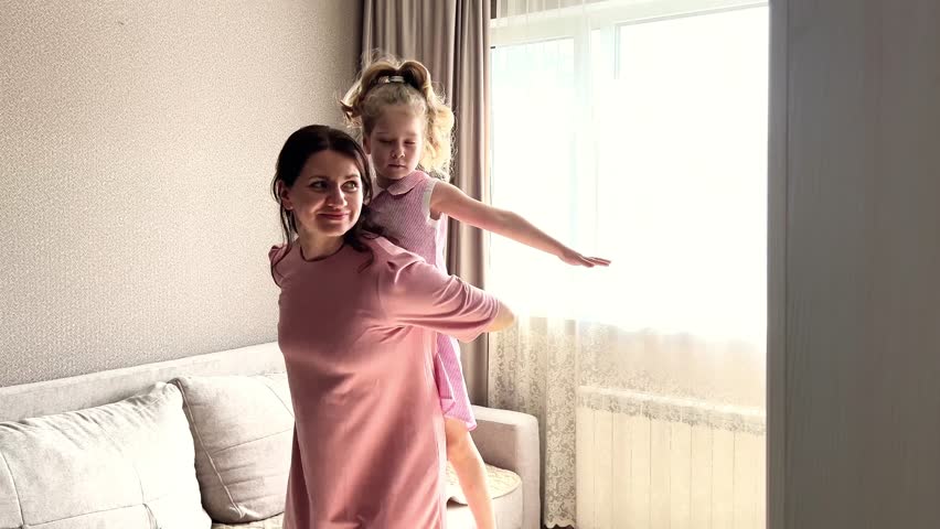 Mom and her small daughter having dance party in living room at home. energetic mother daughter play creating precious memories