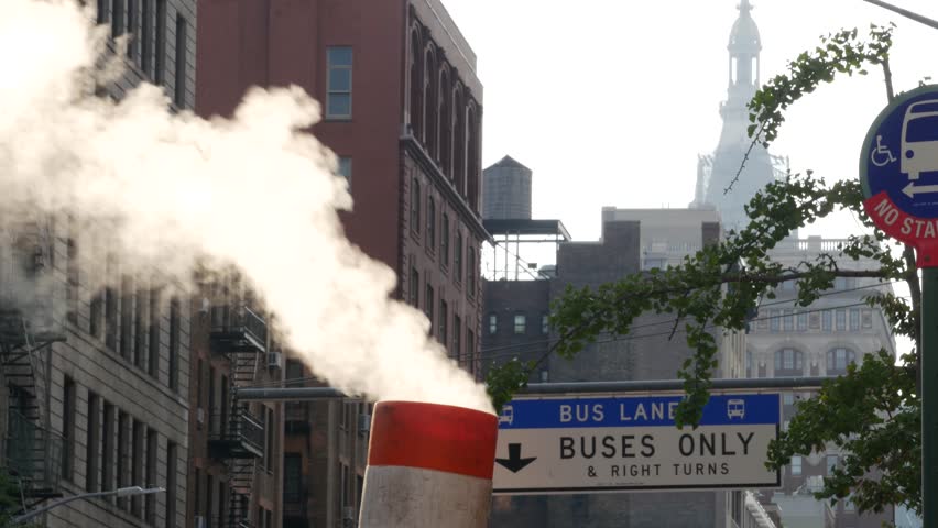 Steam vapor vented on New York City street, orange vapour tube stack. Hot smoke from pipe. Con Edison