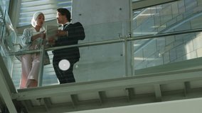 Two business colleagues examining tablet on glass railing, with network icons showing data flow. Innovation, collaboration, corporate, technology, connectivity, professional, modern - Powered by Shutterstock - Get 15% off with code: PIKWIZARD15