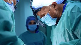 Two bearded surgeons in surgical loupes, caps and masks work at operation. Close up. Medical team performs maxillofacial surgery. - Powered by Shutterstock - Get 15% off with code: PIKWIZARD15