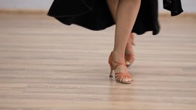 Professional dancer gracefully moving her feet in a dance studio, wearing a black dress and orange heels, close-up - Powered by Shutterstock - Get 15% off with code: PIKWIZARD15