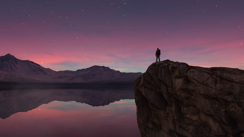 Hiker on a Cliff Overlooking a Mountain Lake at Sunset