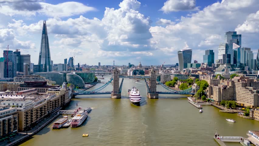Aerial hyper time lapse day view of the lifted open Tower Bridge and city skyline of London, England, with river and people traffic