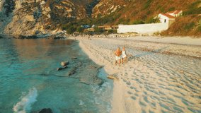 Couple walks along Petani Beach on a warm evening with waves gently touching the sand in Kefalonia - Powered by Shutterstock - Get 15% off with code: PIKWIZARD15