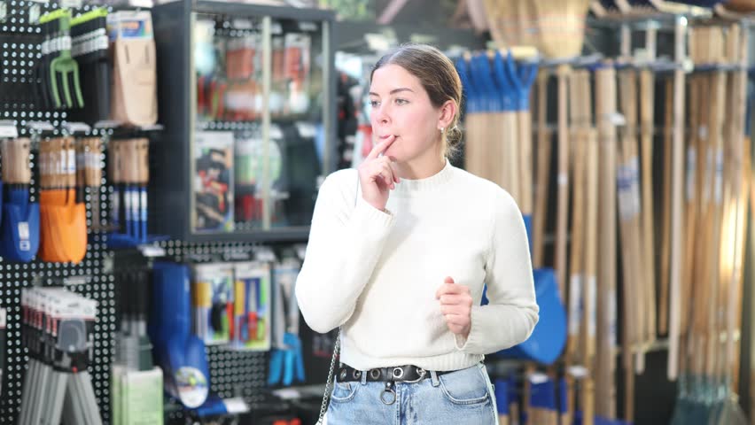 Young woman choosing tools for gardening. Customer came to the sale in the garden section of the supermarket. High quality 4k footage