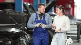 Female mechanic makes a plan together with a male mechanic about the repair and maintenance of the car. Mechanics plan to inspect the engine, change the oil and check the mechanics. High quality 4k - Powered by Shutterstock - Get 15% off with code: PIKWIZARD15