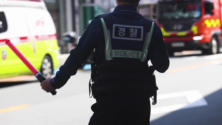 Korean police squad formation in uniform with "Police" logo, policemen maintain order and regulate traffic on incident and fire blaze site, crime scene, rescue operation in Busan city, South Korea 