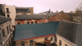 Elevated perspective over ageing Daugavpils back-lot: rusted corrugated roofs, cracked plaster walls and stacked pallets below. Daugavpils, Latvia (Daugavpils, Latvija) - Powered by Shutterstock - Get 15% off with code: PIKWIZARD15
