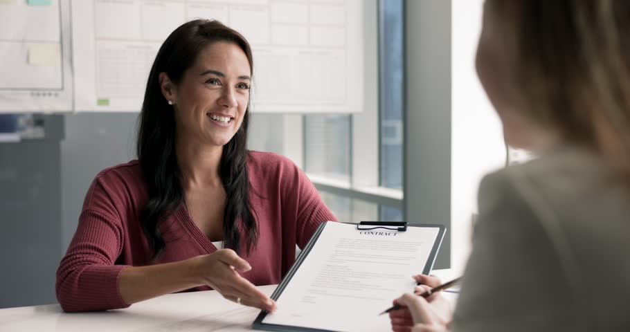 Positive successful Hispanic sales agent showing paper contract to customer. Businesswoman explaining agreement, partnership, cooperation, deal terms to female customer, pointing at document, speaking