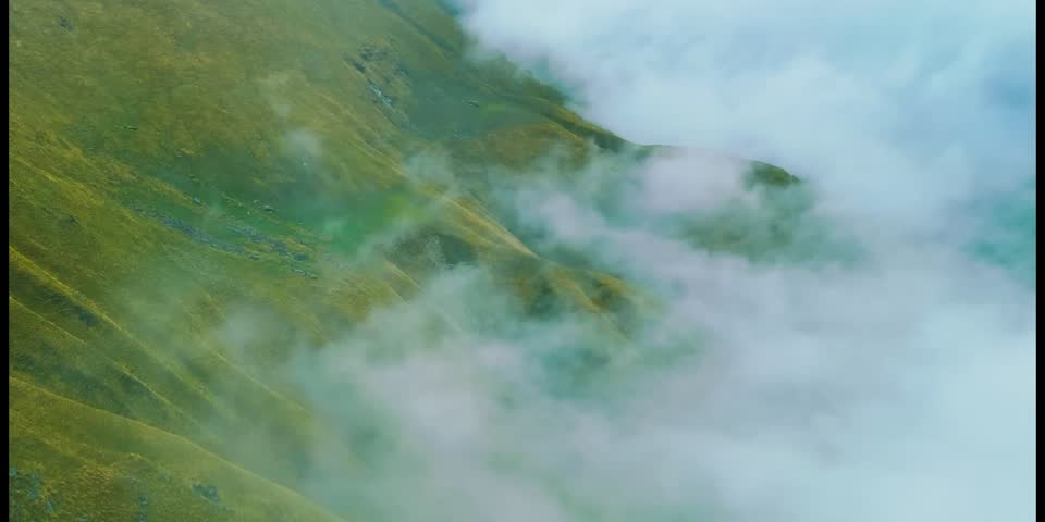 View of clouds moving over green hills.