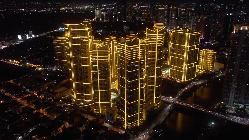 Aerial wide view of Rockwell Center skyscrapers in Makati, Metro Manila, glowing with lights at night and surrounded by the vibrant energy of the city skyline.