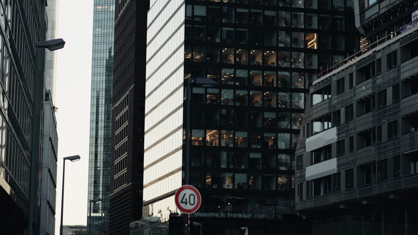 Modern glass buildings in Frankfurt’s financial district with illuminated offices at dusk. Captures the city’s corporate energy, late work culture, and vibrant business life.