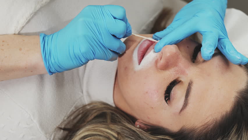 Professional permanent make-up procedure. Tattoo lips makeup treatment in modern beauty salon.