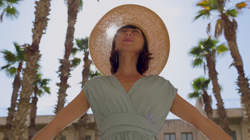 Young girl spinning with open arms in the city. Beautiful woman enjoying the moment. Girl in a hat