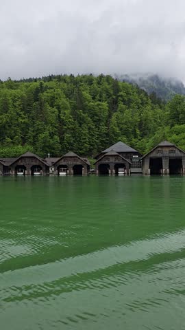 Wooden boathouses on Lake Koenigssee reflect in clear alpine waters,   Bavarian Alps in Berchtesgaden National Park, Germany.