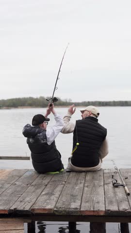 Father teaching his child to fish on the river. Happy family having a good time fishing.  Family and fatherhood concept. Vertical video.
