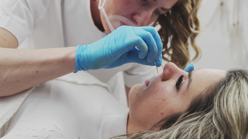 Professional permanent make-up procedure. Tattoo lips makeup treatment in modern beauty salon.