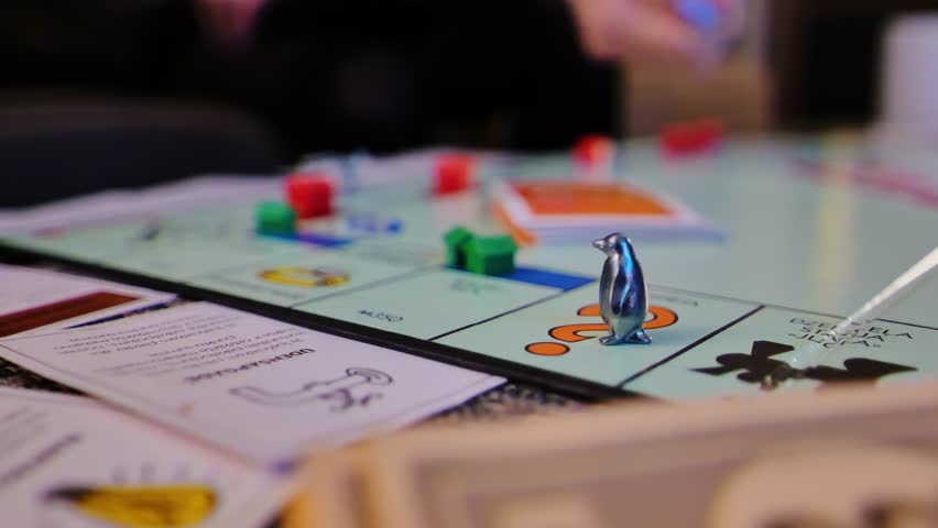 Fun Monopoly game in progress with penguin token, dice roll, and cards on table