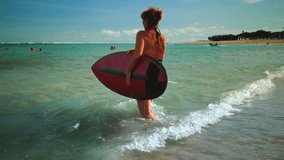 Old woman walks along a sandy beach with a surfboard. Senior female in swimsuit goes surfing on ocean or sea waves. Sandy bali coast, nusa dua beach. - Powered by Shutterstock - Get 15% off with code: PIKWIZARD15