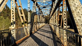 Metal truss bridge walkway in evening light with forest view on golden hour - Powered by Shutterstock - Get 15% off with code: PIKWIZARD15