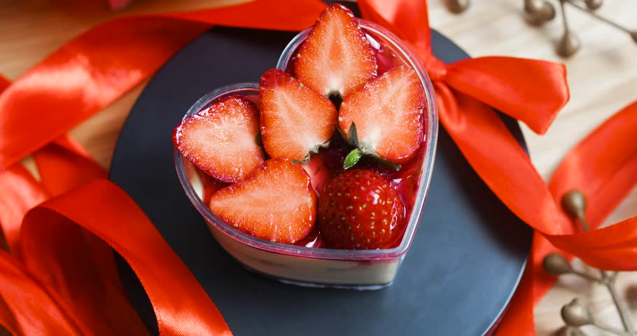 Heart shaped pastry brimming with ripe strawberries, glistening with fruity glaze and accented by delicate orange ribbons, symbolizing romantic culinary artistry