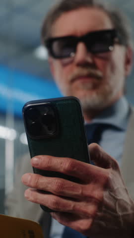 Airport Terminal: Successful Businessman Scanning Boarding Pass Using Smartphone, Checking Flight Information. Entrepreneur Sitting in VIP Departure Lounge. E-Ticket Technology. Close Up Vertical Shot