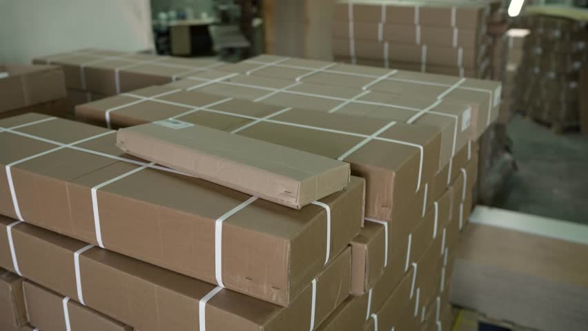 Single cardboard box sliding down a large stack of other boxes in a warehouse or storage facility