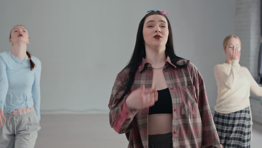 Medium long shot of gen Z group of Caucasian girls in streetwear practicing dance moves in modern studio