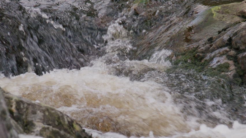 Violent splash of mountain stream water colliding with rock surface in slow motion revealing nature’s raw intensity