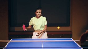 Indian happy young adult gen z athlete player woman hold racket play table tennis with male passing the ball indoor dark room. Sporty teen age girl do sports training exercise at tournament - Powered by Shutterstock - Get 15% off with code: PIKWIZARD15