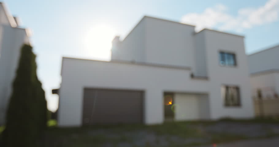 A hand with a keychain in the shape of a small house and keys against the background of house.