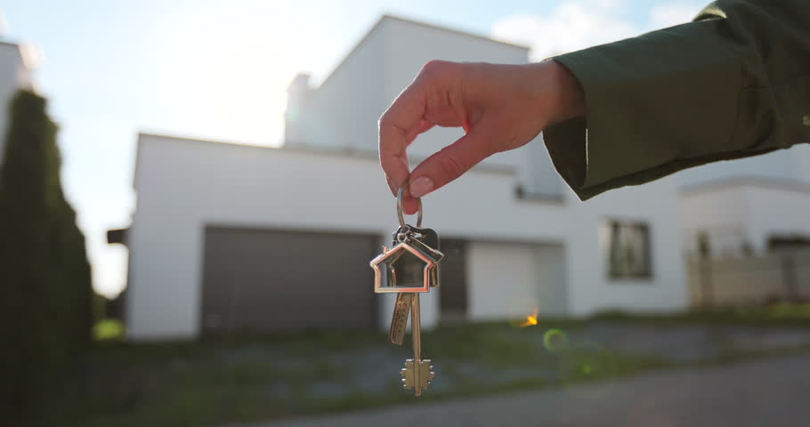 Woman holding keys to new house. Moving to a new home, mortgage, buying real estate, renting and booking housing, dream of living in the village.