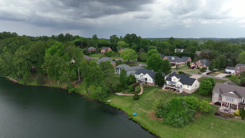 Single Family houses with hilly garden and lake access. Luxury noble american suburb housing area during cloudy day. Aerial approaching shot. Balcony and yard.