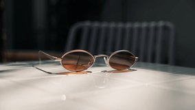 Close up girl hand picks up sunglasses from white table where sunlight falls. - Powered by Shutterstock - Get 15% off with code: PIKWIZARD15