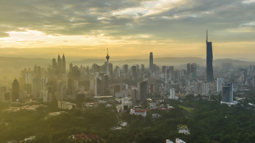Time lapse: Silhouette of KL cityscape view during misty morning overlooking the city skyline from afar with yolk sun and lushes green in the foreground. Kuala Lumpur, Malaysia. Prores 4KUHD