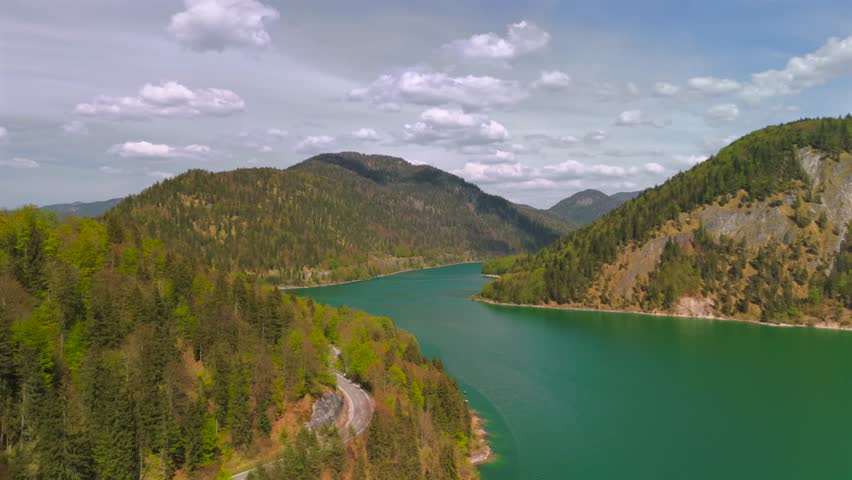 Staudamm am Sylvensteinspeichersee und der Sylvensteinsee in Bayern, Deutschland Lenggries. Dam and observation deck on a large reservoir Sylvensteinsee in Bavaria, Germany on sunny spring day. 