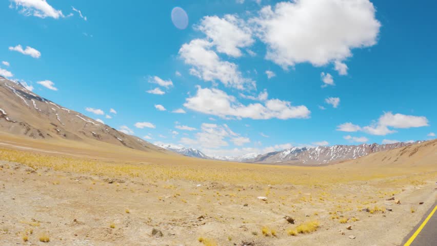 4K shot of clouds above the snowy Himalayan mountain peaks as seen from More Plains on Leh Manali highway during a sunny day at Ladakh, India. Scenic view of the Himalayas in Ladakh during summer.
