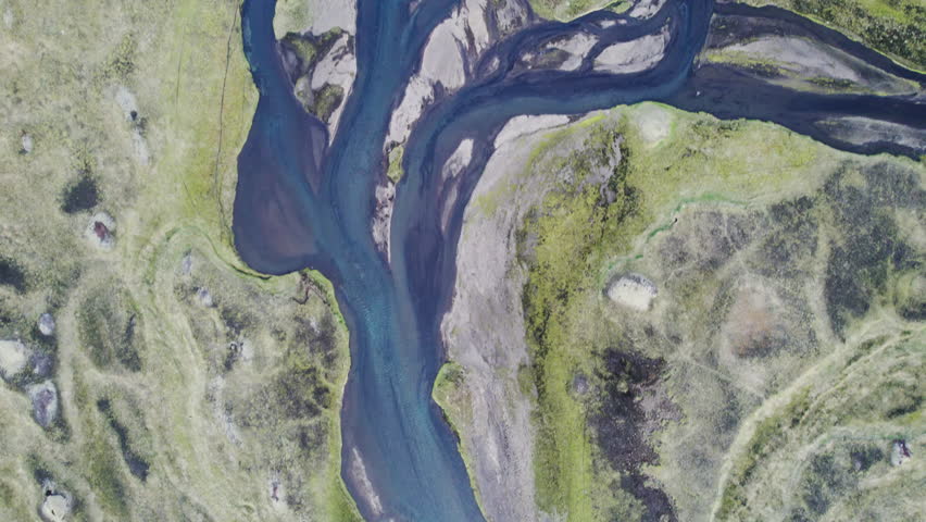 Aerial view of winding river glacier flowing among mossy wilderness during summer at Icelandic Highlands