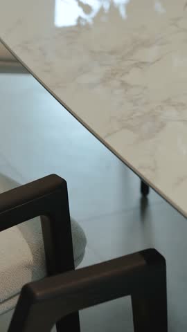 Close-up of a luxurious marble white dining table. Stylish marble tabletop is beautifully paired with sleek. Vertical video