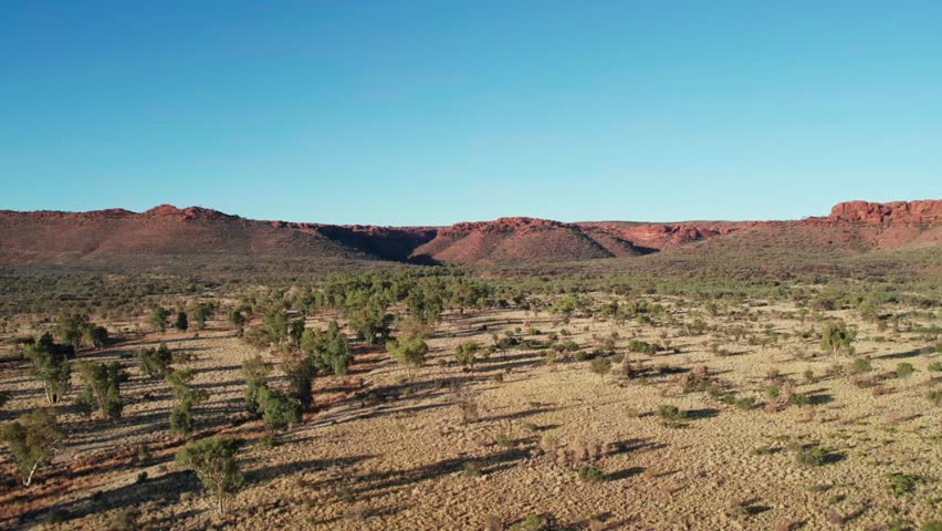 Rising drone footage of landscape with Kings Canyon, Watarrka in the distance, Northern Territory, Australia. August 2022.