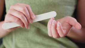Close up view of woman s hands gently filing nails while wrapped in green towel, fine nail dust visible in motion, indoor setting with natural lighting, expressing calm grooming and personal care - Powered by Shutterstock - Get 15% off with code: PIKWIZARD15