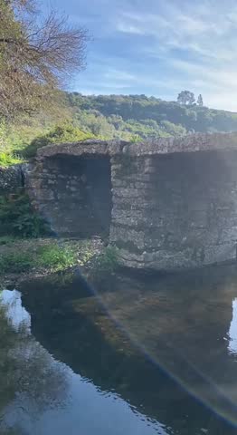 Ancient Roman stone bridge spanning a mountain river in Portugal, surrounded by scenic hills — a timeless blend of history, nature, and architecture in a peaceful countryside landscape.