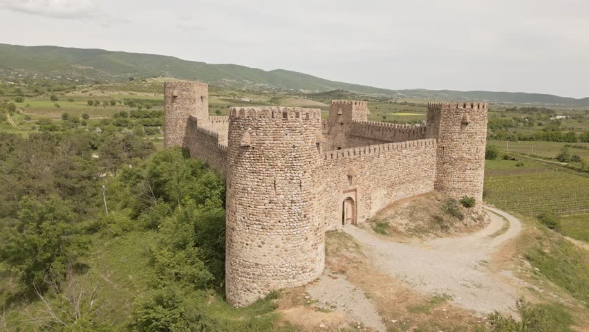 Aerial rising view Chailuri Castle, known as Niakhura Fortress, stands in eastern Georgia as a medieval stronghold with partial towers and thick stone walls. Sagarejo region surrounded by vineyards