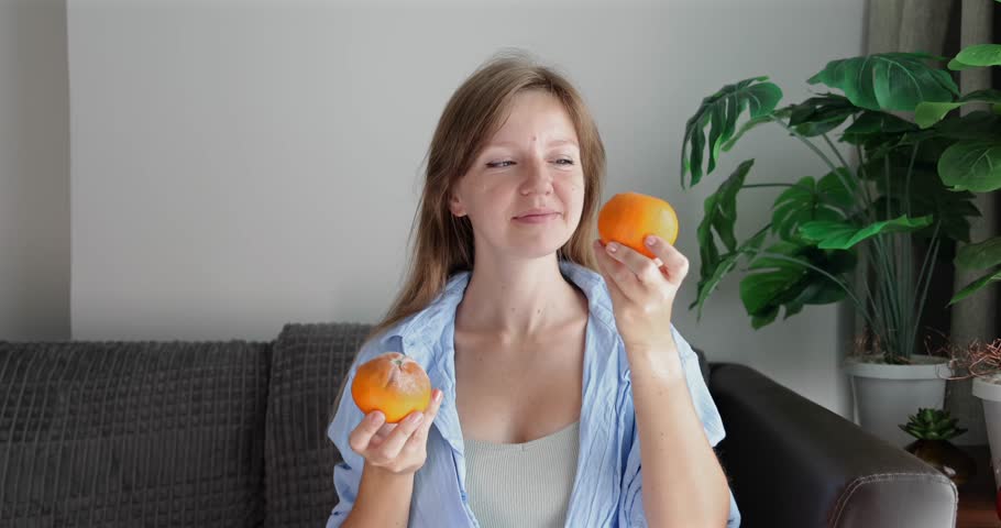 Woman savoring fresh persimmons indoors, seasonal fruit enjoyment, cozy home atmosphere, wellness and lifestyle imagery.