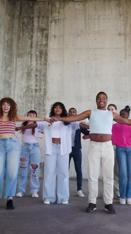 Diverse friends dance to music song for viral social media video. Young people celebrate party. Vertical video