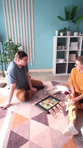 Beautiful young couple having fun playing board game while relaxing and enjoying leisure time together at home