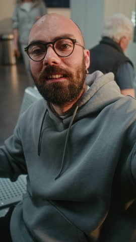 Influencer Popular Travel Blogger Recording Vlog in Crowded Airport Terminal from Trip Using Smartphone, Waiting for Flight in Boarding Lounge. Video Content for Blog, Online Video Chat. Vertical Shot