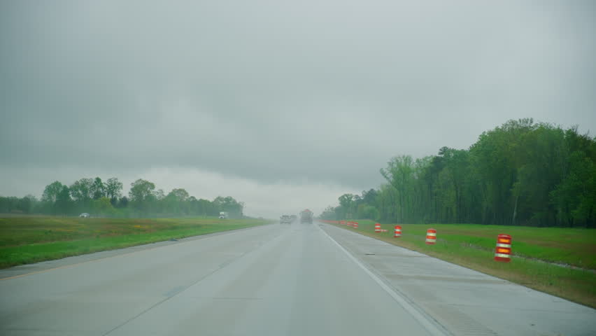 Driving car on highway with construction zone in heavy fog with rain, dangerous weather conditions and limited visibility