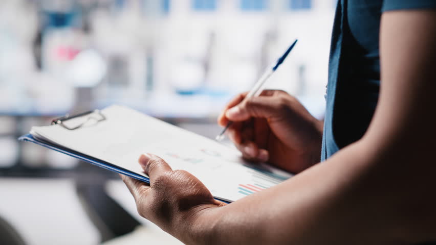 Black photovoltaics factory specialist checking configuration files, analyzing data to ensure seamless production. Solar panels manufacturing plant employee reading user manual. Camera A.